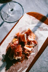 Close-up of sliced Serrano ham on a wooden board, perfect for charcuterie platters.